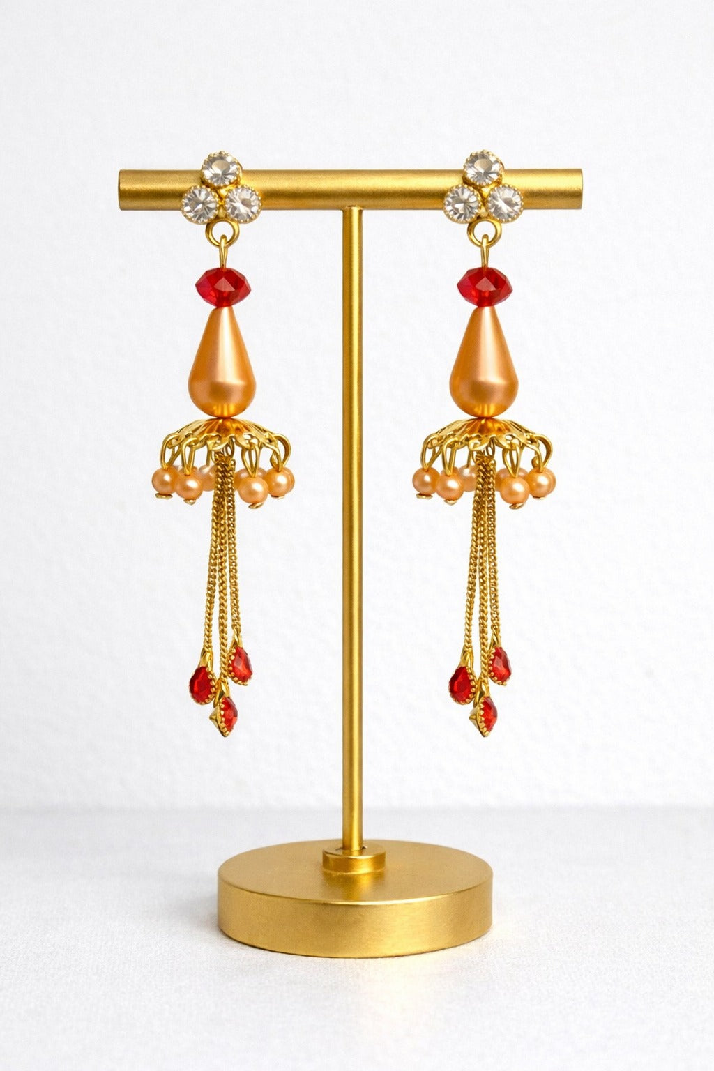 Elegant Gold Jhumka Earrings with Red Crystal Drops and Chain Tassels